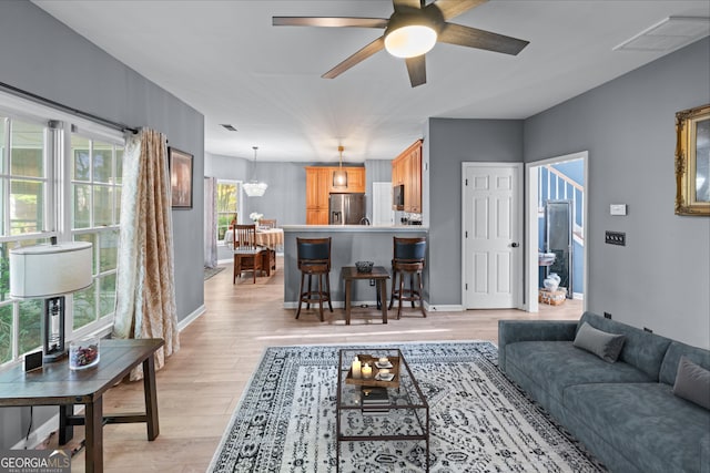 living room featuring light wood finished floors, ceiling fan, baseboards, and visible vents