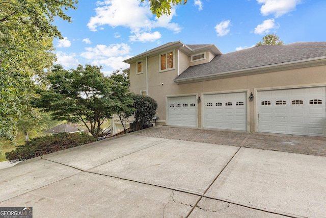 12 Arbor Shrs, Newnan, GA 30265 - view of home's exterior with driveway, stucco siding, a garage, and a shingled roof