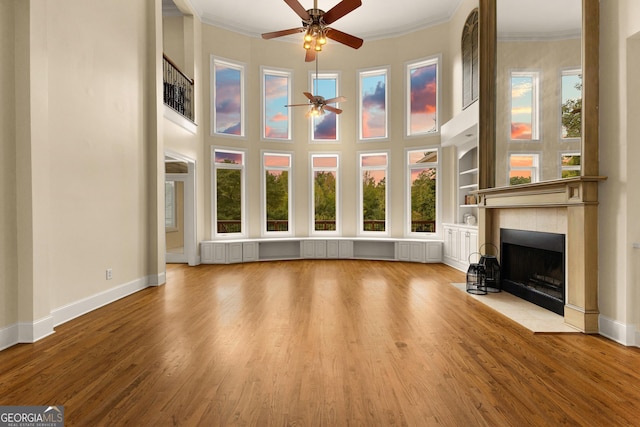 12 Arbor Shrs, Newnan, GA 30265 - unfurnished living room with ceiling fan, wood finished floors, crown molding, a fireplace with flush hearth, and a towering ceiling