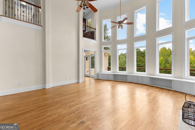 12 Arbor Shrs, Newnan, GA 30265 - unfurnished living room featuring ceiling fan, light wood finished floors, a towering ceiling, and crown molding