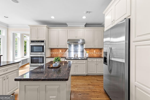 12 Arbor Shrs, Newnan, GA 30265 - kitchen featuring stainless steel appliances, ornamental molding, under cabinet range hood, light wood-type flooring, and decorative backsplash