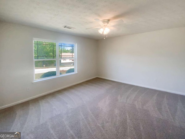 unfurnished room featuring carpet, visible vents, baseboards, and ceiling fan