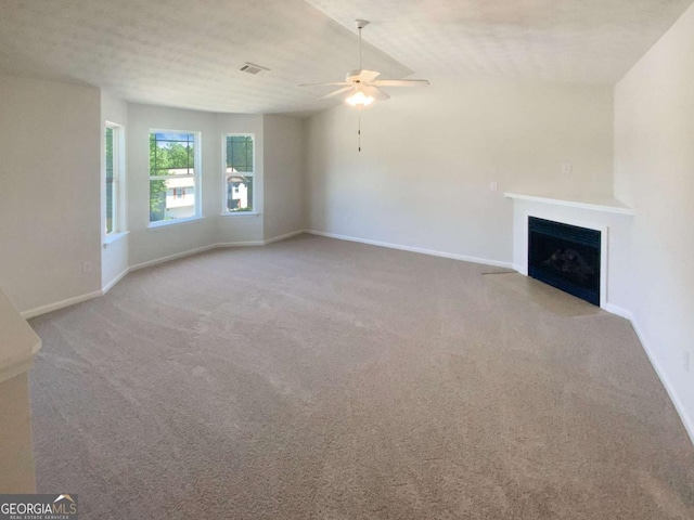 unfurnished living room featuring a fireplace with flush hearth, baseboards, a ceiling fan, and carpet