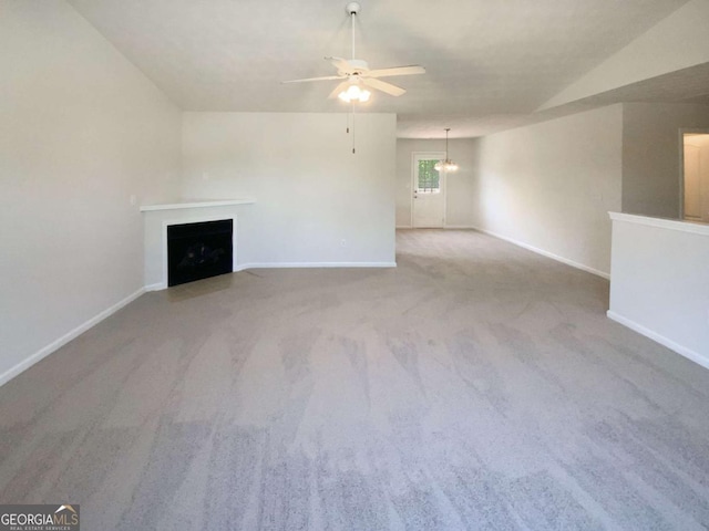 unfurnished living room with carpet flooring, a fireplace with flush hearth, baseboards, and ceiling fan