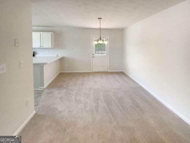 unfurnished dining area featuring a chandelier, light carpet, and baseboards