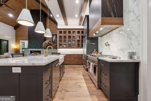 448 Golden Bear Pass, Dahlonega, GA 30533 - kitchen featuring stainless steel appliances, wall chimney exhaust hood, light wood-type flooring, glass insert cabinets, and a large island