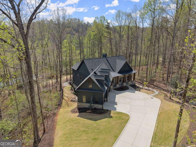 448 Golden Bear Pass, Dahlonega, GA 30533 - rustic home featuring concrete driveway, a wooded view, a chimney, board and batten siding, and a porch