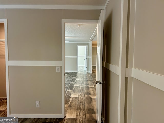 hall with wood finished floors, a textured ceiling, and crown molding