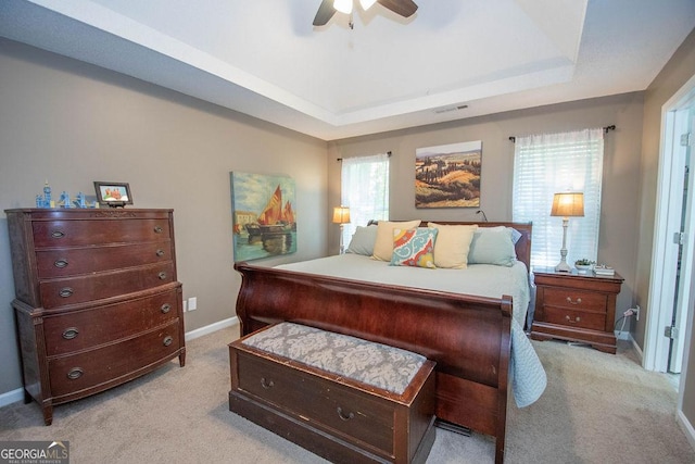 bedroom with light carpet, a tray ceiling, visible vents, and baseboards