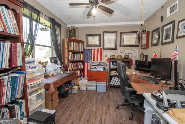 home office with wood finished floors, visible vents, a textured ceiling, and ceiling fan