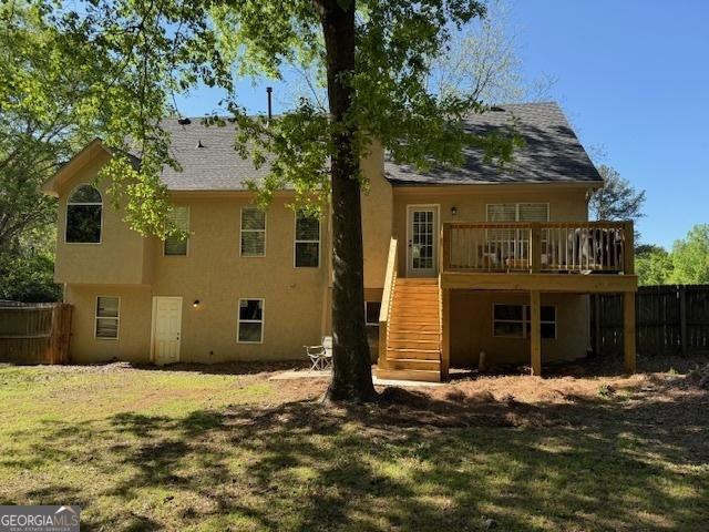 rear view of property featuring fence, a wooden deck, stucco siding, and stairway