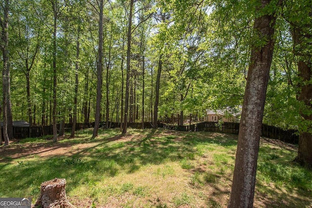 view of yard with a wooded view and a fenced backyard