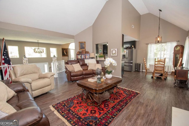 living area with wood finished floors, high vaulted ceiling, and an inviting chandelier