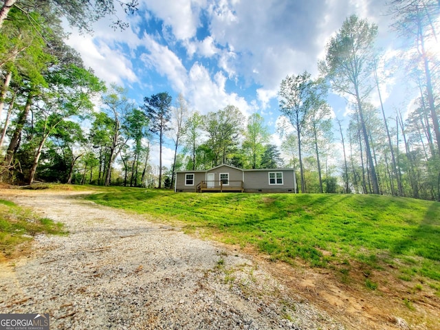 manufactured / mobile home featuring crawl space, gravel driveway, and a front lawn