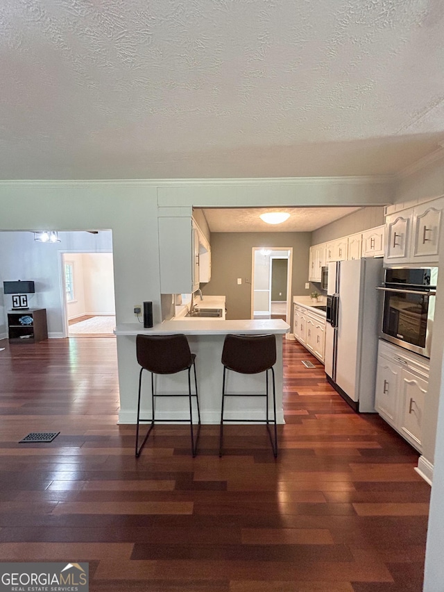 3411 Ponderosa Rd, Portal, GA 30450 - kitchen featuring stainless steel oven, white refrigerator with ice dispenser, dark wood-style flooring, a textured ceiling, and white cabinetry