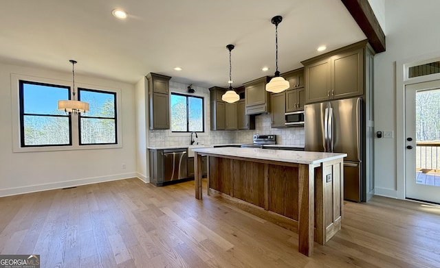 kitchen featuring baseboards, a center island, light wood-type flooring, stainless steel appliances, and backsplash