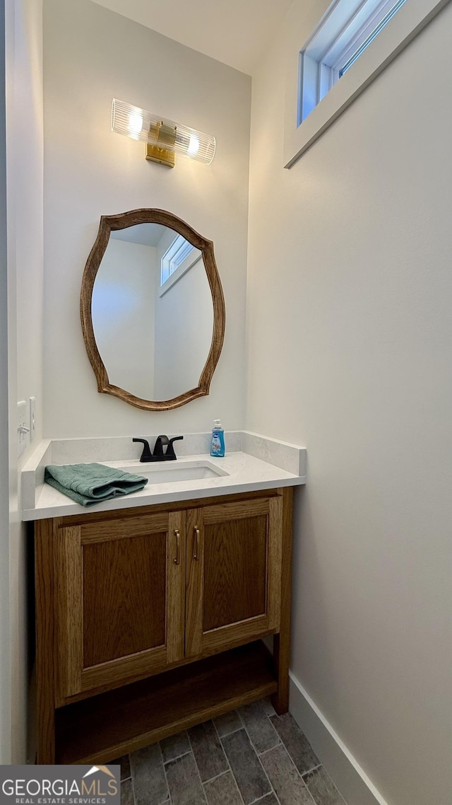 bathroom with vanity, baseboards, and stone finish flooring