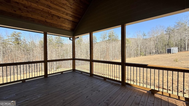 wooden terrace featuring a wooded view and an outbuilding