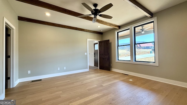 spare room featuring visible vents, baseboards, a ceiling fan, beam ceiling, and light wood-style flooring