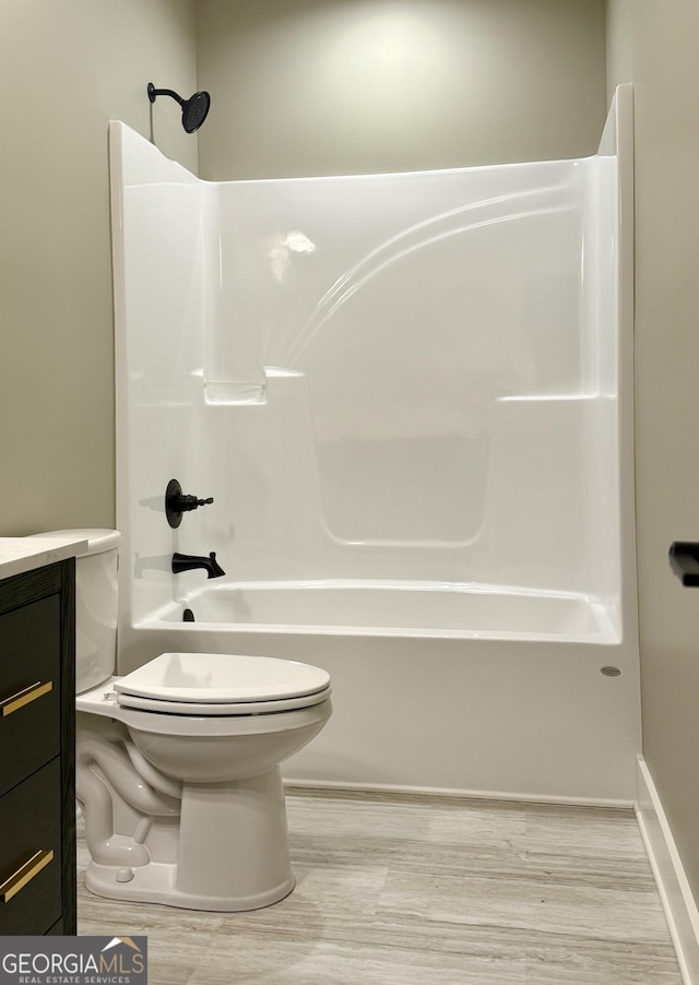 full bathroom with tub / shower combination, vanity, toilet, and wood finished floors