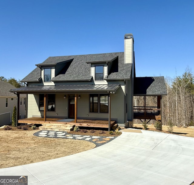 view of front of property with a standing seam roof, covered porch, metal roof, a chimney, and a shingled roof