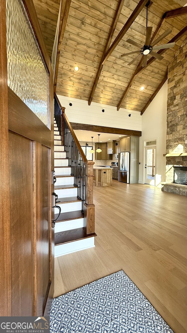 stairs featuring high vaulted ceiling, wooden ceiling, a ceiling fan, and wood finished floors