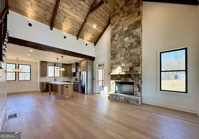 unfurnished living room featuring visible vents, light wood-style flooring, high vaulted ceiling, and baseboards