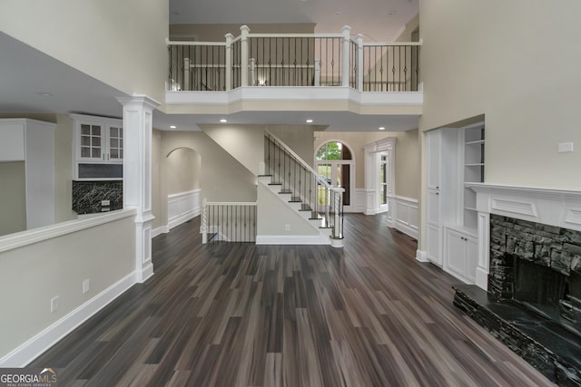 6048 Golf View Xing, Locust Grove, GA 30248 - unfurnished living room featuring a fireplace, stairway, dark wood-style flooring, a high ceiling, and arched walkways