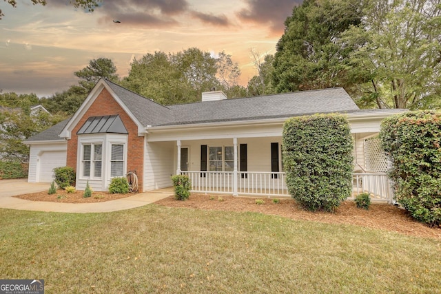 ranch-style house with a chimney, a front lawn, an attached garage, brick siding, and a porch