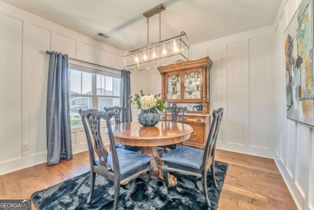 1302 Gardenia Ct, Villa Rica, GA 30180 - dining space with a decorative wall, visible vents, a chandelier, and light wood-style floors