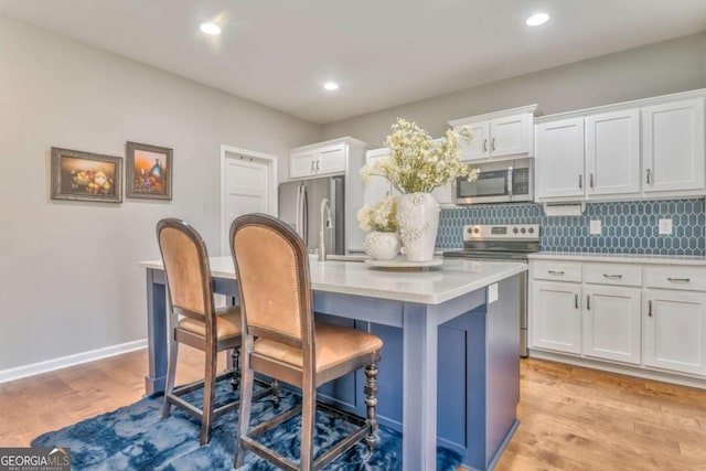 1302 Gardenia Ct, Villa Rica, GA 30180 - kitchen featuring appliances with stainless steel finishes, a kitchen island with sink, light countertops, and white cabinetry