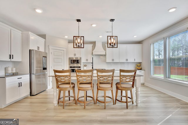196 Saddleridge Trl, Senoia, GA 30276 - kitchen featuring a chandelier, premium range hood, white cabinetry, a kitchen bar, and appliances with stainless steel finishes