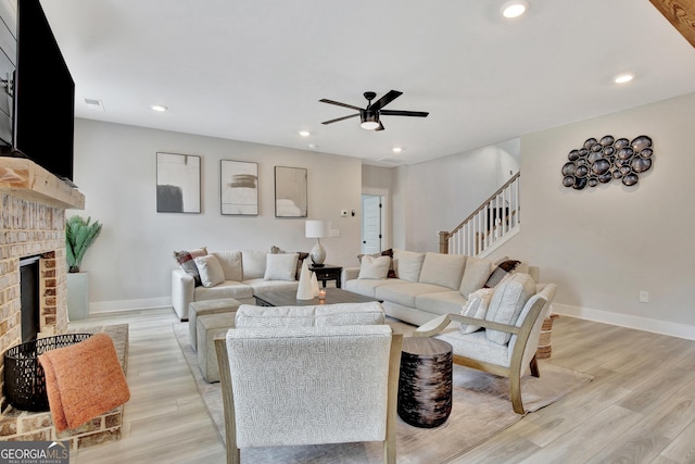 196 Saddleridge Trl, Senoia, GA 30276 - living area featuring baseboards, a brick fireplace, ceiling fan, light wood finished floors, and stairs