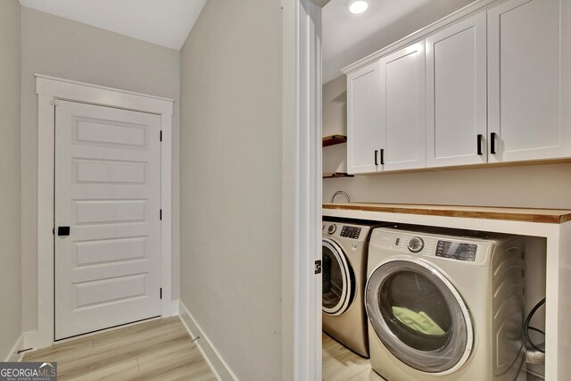 196 Saddleridge Trl, Senoia, GA 30276 - laundry room with light wood-style flooring, baseboards, washing machine and clothes dryer, and cabinet space