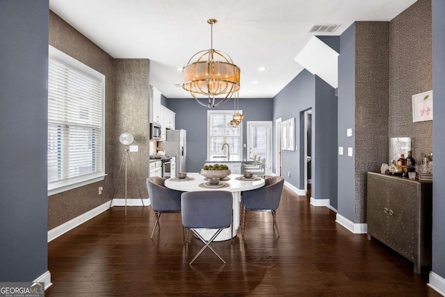 dining area with baseboards, a notable chandelier, dark wood finished floors, and visible vents