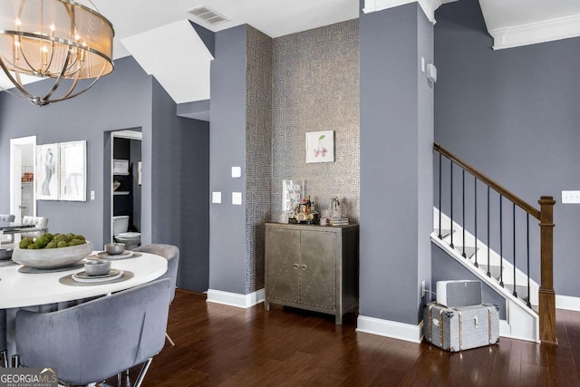 dining space with stairway, visible vents, a high ceiling, and wood finished floors