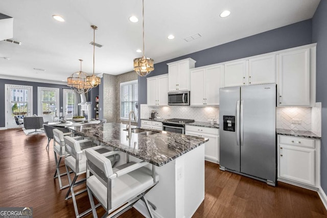 kitchen with a sink, visible vents, decorative backsplash, and stainless steel appliances