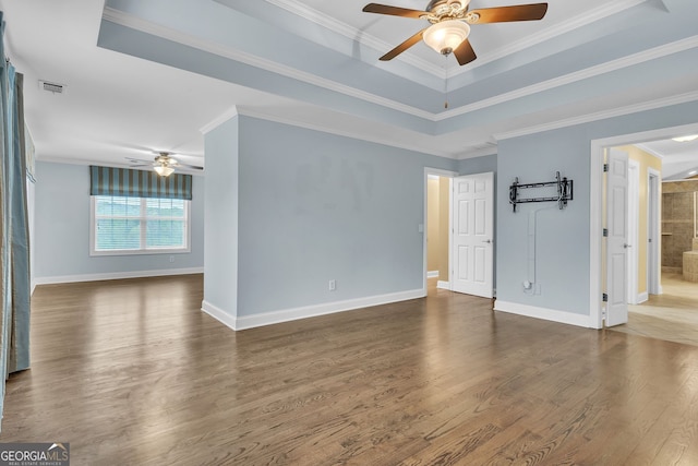 empty room featuring a tray ceiling, a ceiling fan, visible vents, baseboards, and dark wood finished floors