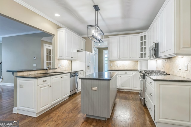 kitchen with stainless steel appliances, ornamental molding, a peninsula, and a sink