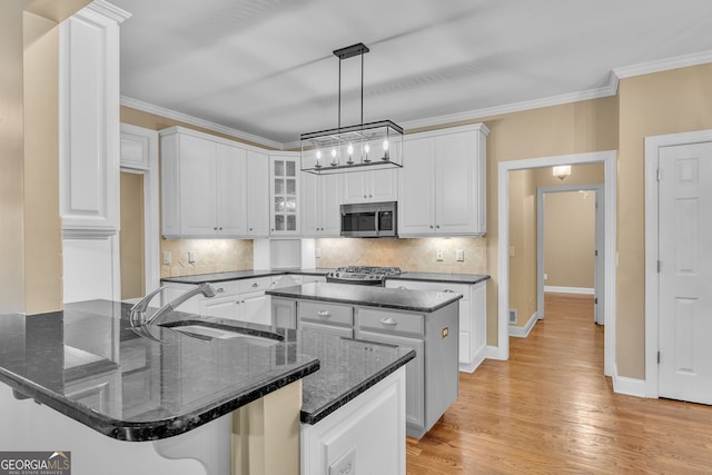 kitchen featuring white cabinetry, an inviting chandelier, a sink, and stainless steel microwave