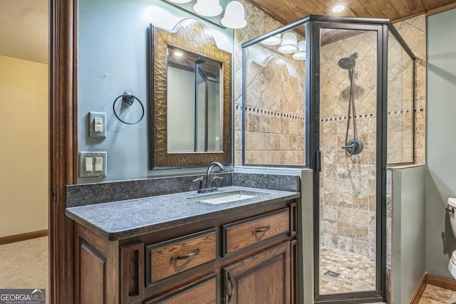 bathroom featuring toilet, a shower stall, vanity, and baseboards