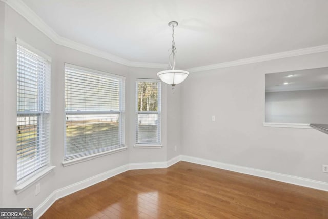unfurnished dining area featuring wood finished floors, baseboards, and ornamental molding