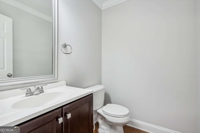 half bath with vanity, baseboards, ornamental molding, toilet, and wood finished floors