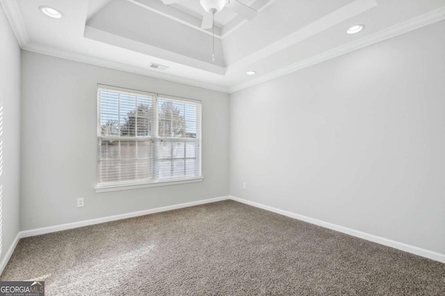 carpeted empty room with a tray ceiling, ceiling fan, baseboards, and visible vents