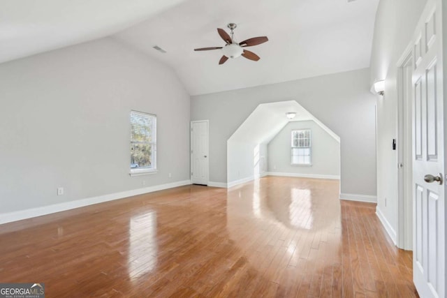 bonus room featuring baseboards, light wood-type flooring, vaulted ceiling, visible vents, and ceiling fan