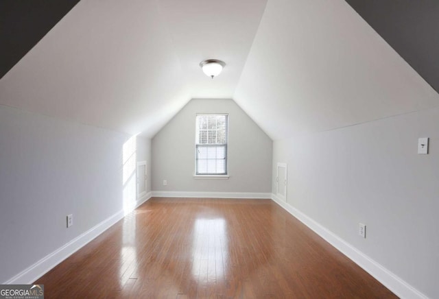 additional living space with wood finished floors, baseboards, and lofted ceiling
