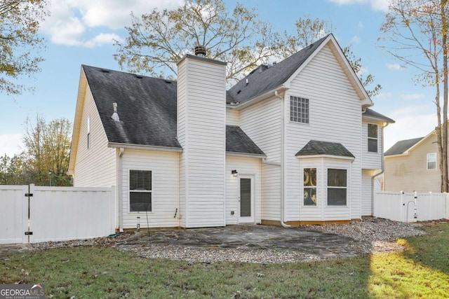 back of house featuring a chimney, a gate, a patio area, a yard, and fence