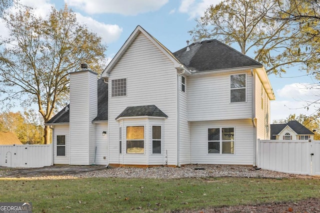 rear view of property featuring fence, a gate, and a lawn