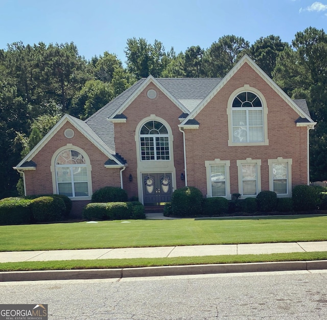 135 Danube Trl, Stockbridge, GA 30281 - view of front of house featuring a shingled roof, a front yard, and brick siding