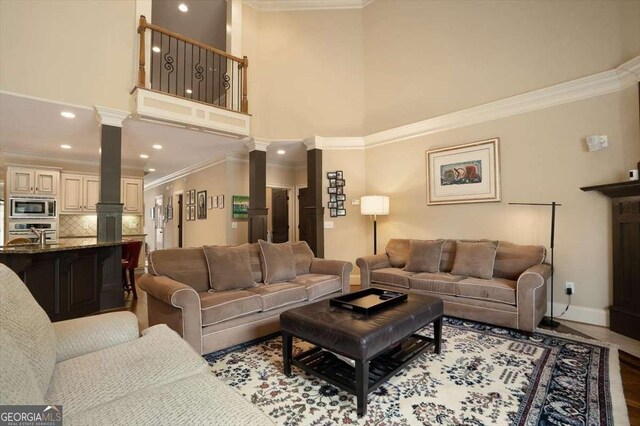 1786 Cambridge Sq, Watkinsville, GA 30677 - living room featuring a high ceiling, decorative columns, baseboards, and ornamental molding